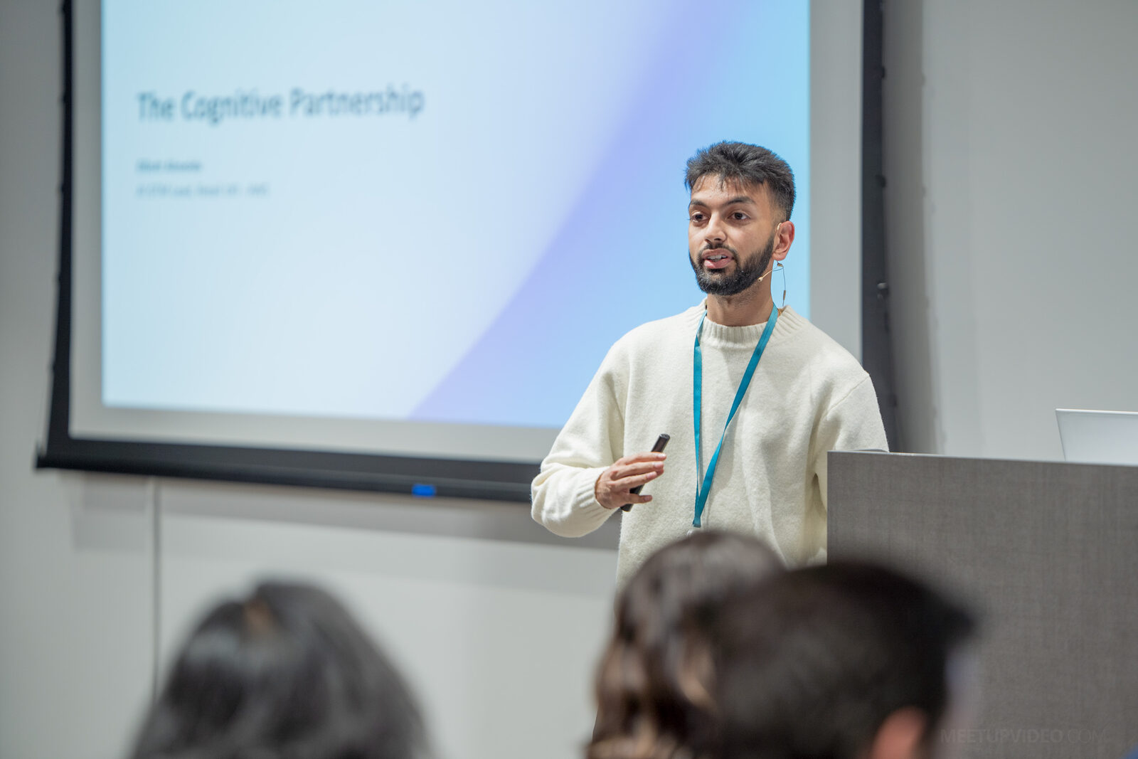 A speaker wearing a headset microphone beside the title slide of a talk called “The Cognitive Partnership”.